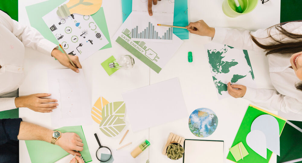 businesspeople-working-on-graph-with-various-natural-resources-icon-on-desk